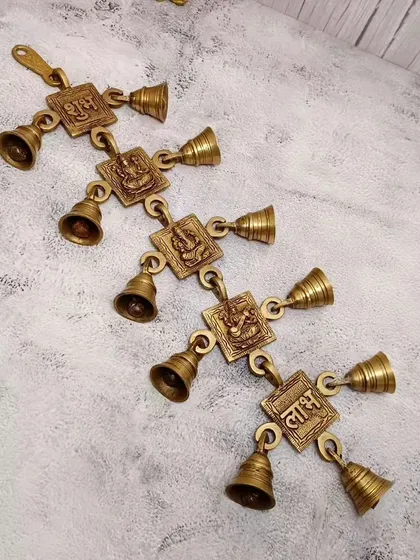 Brass se bana yeh Shubh Labh wall hanger hai, jiske saath Lakshmi, Ganesha, aur Saraswati ke mukh aur ghantiyan lagi hain. Ise darwaze par lagana shubh hota hai.
