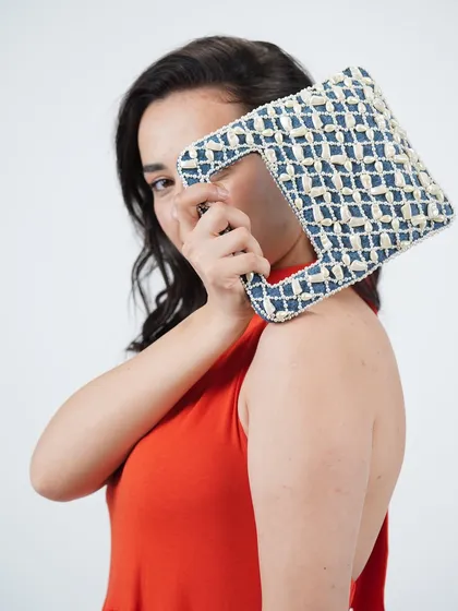 My pearl-embellished denim wrist bag is designed to be a conversation starter. Here you can see how the unique cutout handle design looks when held, adding a modern and playful touch to your style.