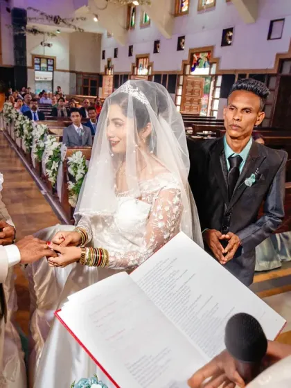 A close-up of the ring exchange during a Catholic ceremony, with the priest guiding the couple. This shot focuses on the symbolic act of commitment.