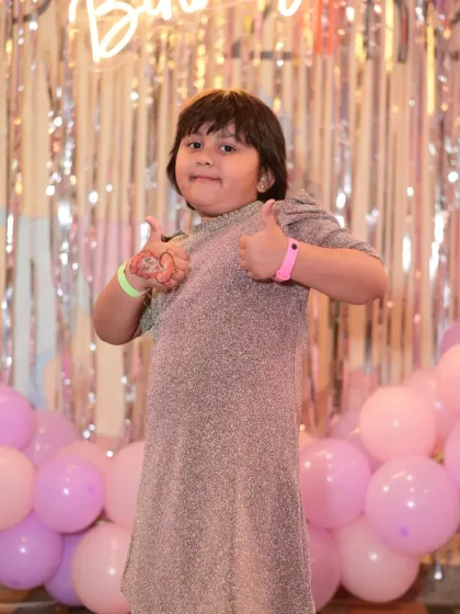 A birthday girl giving a thumbs-up, clearly having a fantastic time at her party.