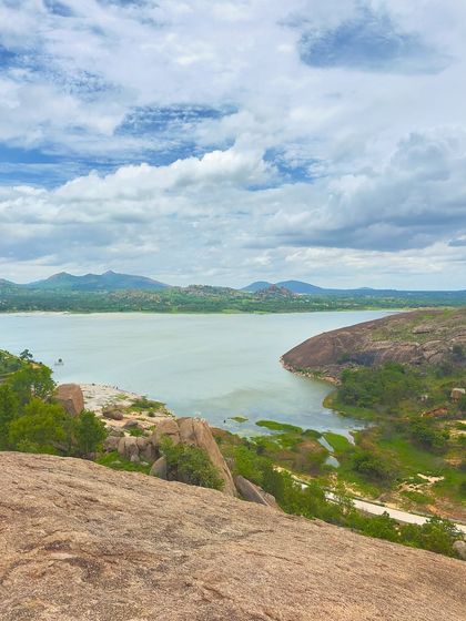 The view from Mandaragiri Hill, overlooking a tranquil lake surrounded by rocky terrain and greenery.