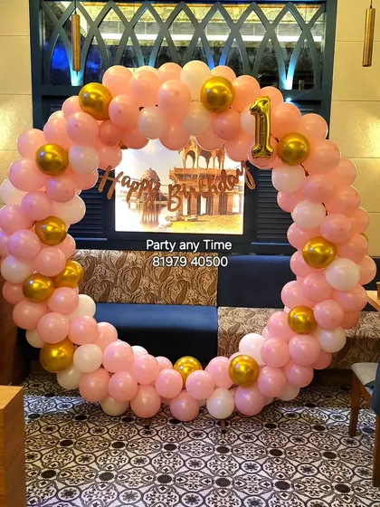 A simple pink, white, and gold circular balloon arch set up in a restaurant.