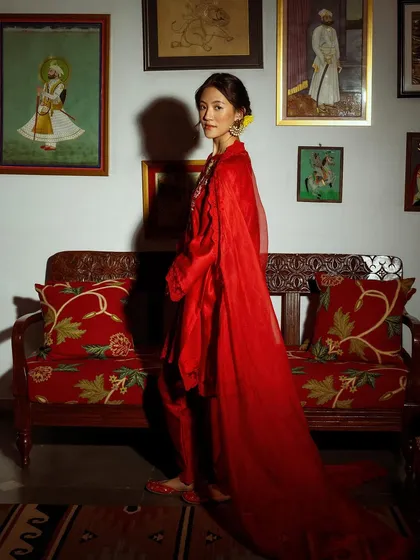 A side profile of the flowing red outfit, capturing its graceful movement. This shot emphasizes the drama and elegance of the cape.