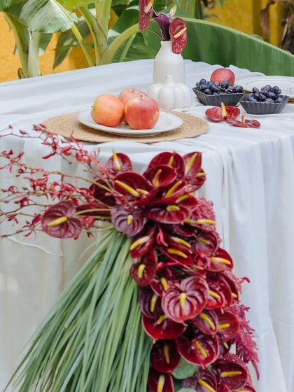 The rich red of the anthurium floral runner contrasts beautifully with the crisp white tablecloth and fresh apples on the Orchard Table.