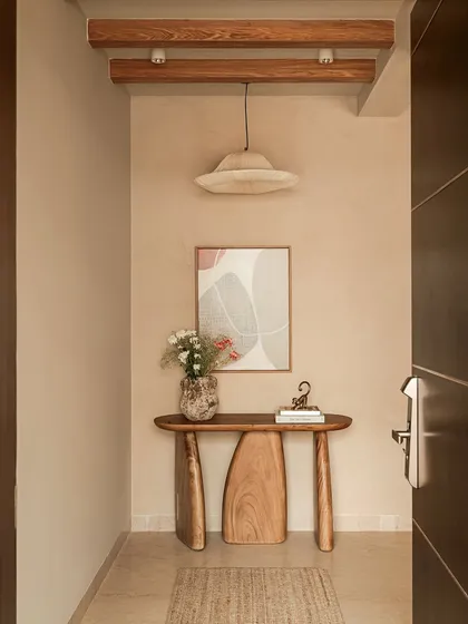The experience of a home begins the moment you enter. I designed this entryway with a handcrafted sculptural wood console and exposed ceiling beams to create a warm, welcoming transition that celebrates natural materials and artisanal skill.