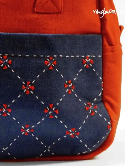 A close-up of the detailed hand embroidery on one of our travel bags. This diamond-grid pattern with floral accents is created with a simple running stitch, adding both beauty and strength to the upcycled fabric.