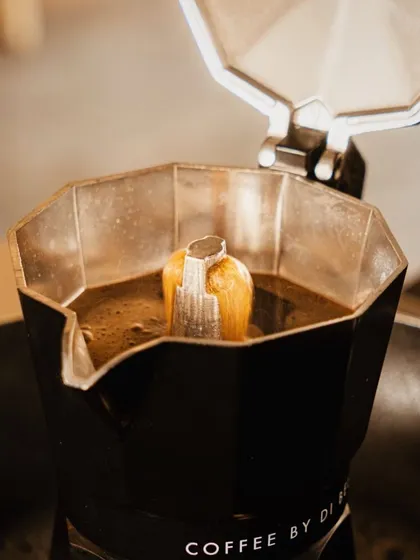 A tight shot looking into a moka pot as it brews. This image captures the authentic, aromatic process of making fresh coffee, appealing to true coffee enthusiasts who appreciate the details.