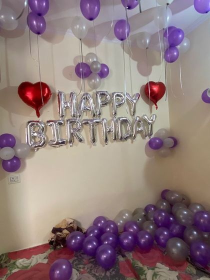 A simple yet beautiful room decoration using purple, silver, and red heart-shaped balloons. The balloons scattered on the floor add a playful and festive touch to the surprise.