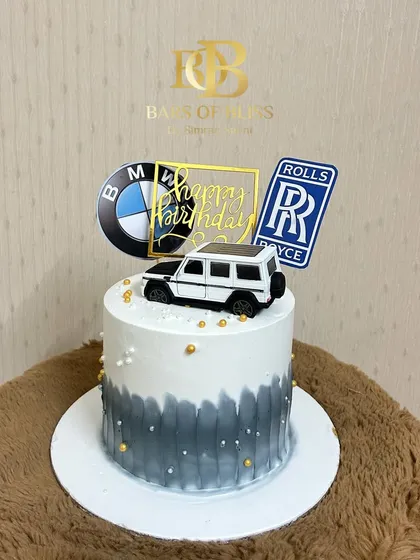 A sleek and stylish cake for the luxury car enthusiast. This design features a grey and white watercolor effect, topped with logos of premium car brands like BMW and Rolls Royce, and a model G-Wagon.