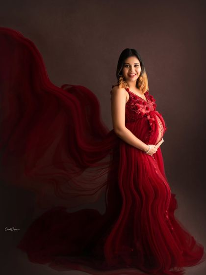 The flow of the fabric in this shot is just breathtaking. This mom-to-be is all smiles in a vibrant red gown with floral appliqué details.