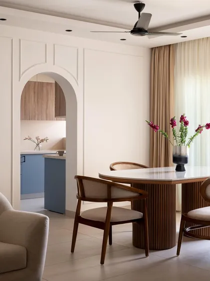 This view from the dining area into the kitchen highlights an open-concept living design. The fluted wood dining table complements the kitchen's textures, creating a cohesive and inviting space for family gatherings.