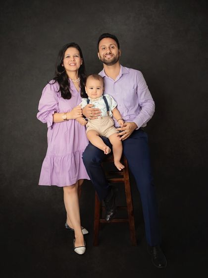 A classic family-of-three portrait against a simple black backdrop. This timeless style ensures the focus remains entirely on the family's connection.