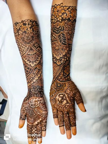 This photo shows both the front and back of bride Sunera's mehendi. One palm features the groom's initial, while the other has her name written in beautiful calligraphy.