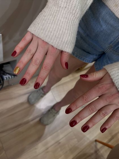 A close-up of one of the festive manicures we did for the RCB team, featuring a classic red with a gold glitter accent nail.