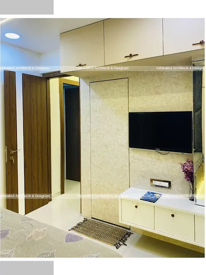 A view of the master bedroom in Majestic Villa, showing the TV unit and dressing table integrated into the wardrobe wall. This creates a seamless and clutter-free look.
