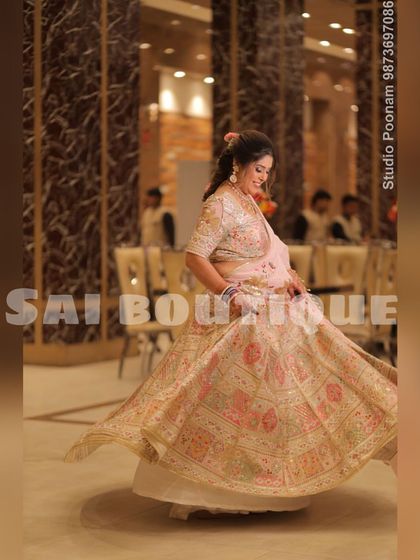 The bride's mami looking graceful in a custom pastel pink and cream lehenga. The intricate embroidery and the flowy silhouette make it a perfect choice for a family wedding.