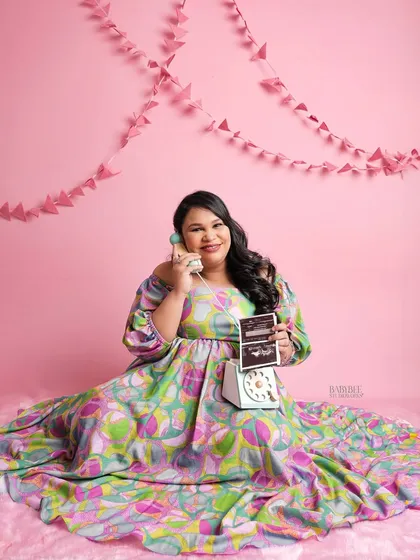 Let's have some fun. This playful, retro-themed shot uses a vibrant pink backdrop and a vintage phone prop for a unique and colorful maternity photo.