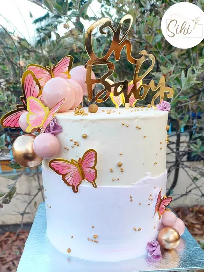 "Oh Baby." A beautiful and modern baby shower cake. The design features a soft lavender ombre, edible pink butterflies, and decorative baubles, all topped with a gold acrylic topper.