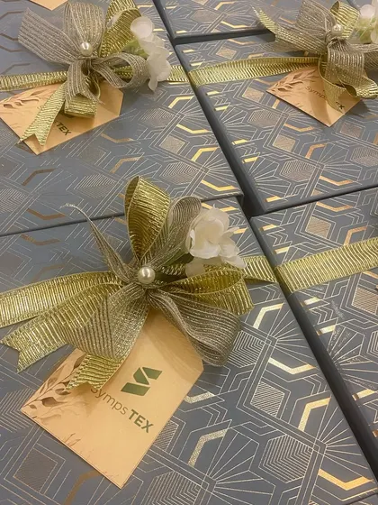 The beautifully wrapped corporate boxes for Symps TEX, complete with a custom tag and a delicate floral and pearl embellishment on the bow.