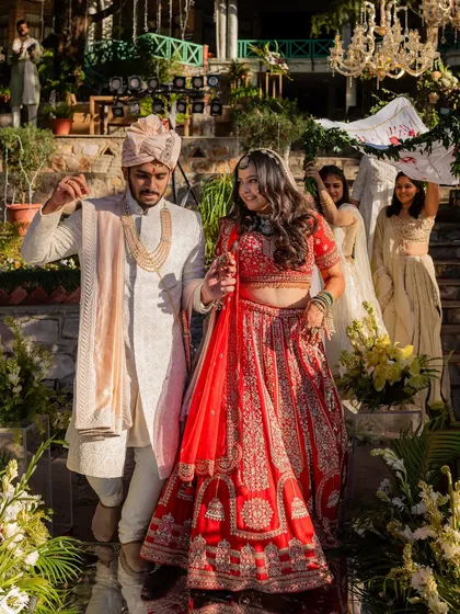 A beautiful shot of the bride's entrance at her destination wedding. Her hair is styled in soft, open waves under her dupatta, a perfect choice for a daytime ceremony.