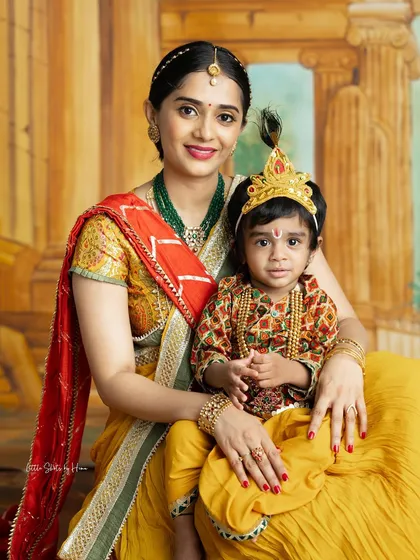 A mother with her little boy dressed as Krishna. The vibrant colors of their traditional outfits make this a joyful and eye-catching portrait.
