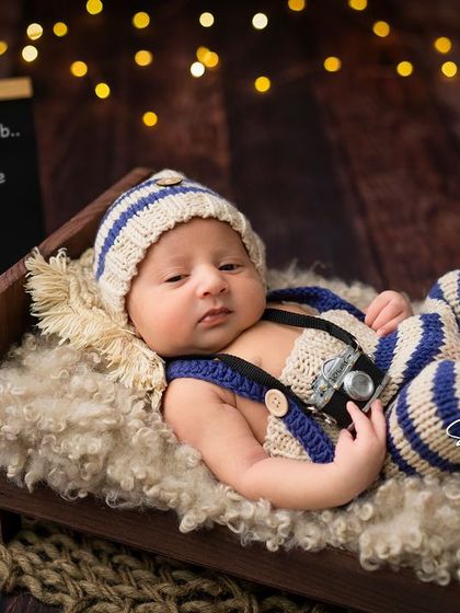 "Don't disturb, the prince is here." A fun and adorable shot of an awake newborn in a cute striped outfit.