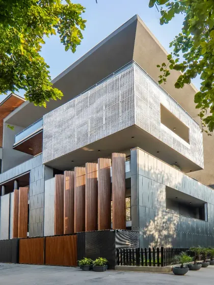 This facade in Sushant Lok, Gurgaon, is a study in volumes and materials. The design features a unique tapered projection, aluminum louvers, and textured tiles, creating a visually compelling composition that plays with light and shadow.