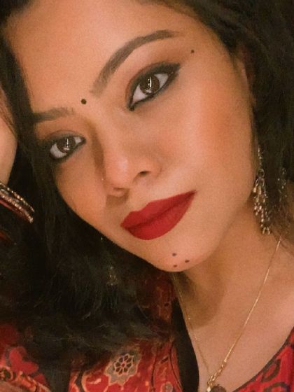 A close-up portrait capturing the festive makeup, with bold eyes and a red lip, complemented by traditional jewelry.