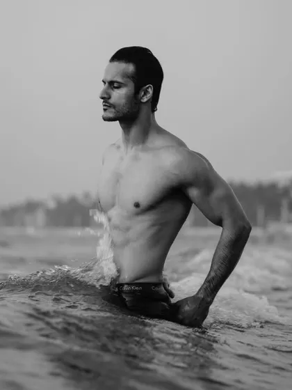 Monday blues. A powerful black and white portrait of a model in the ocean. The moody, overcast light and the waves crashing around him create a dramatic and contemplative feel.
