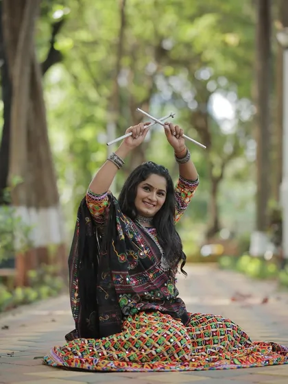 Another playful shot with the dandiya sticks, showcasing the full traditional attire for the Navratri celebration.