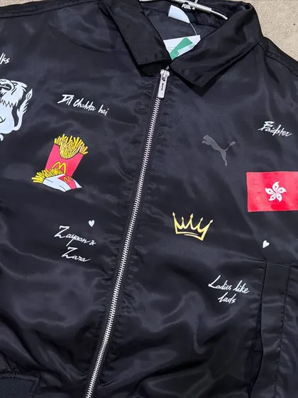 A custom-painted Puma bomber jacket with various personal symbols and text for a client.