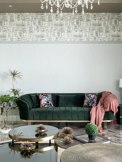 The fluted wall serves as a perfect backdrop for the emerald green sofa. I broke up the vertical lines with a band of architectural wallpaper, a trick that works beautifully in a room with high ceilings.