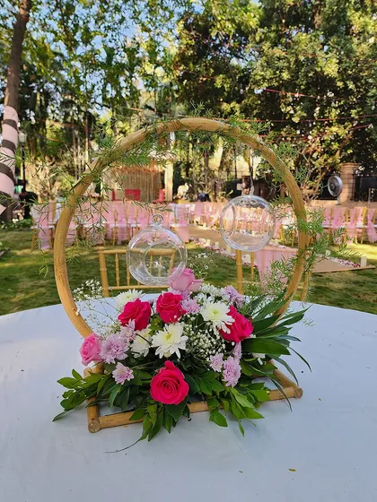 A delicate centerpiece with pink and white flowers set in a bamboo-style hoop. This design is perfect for a daytime garden party or an outdoor wedding luncheon.
