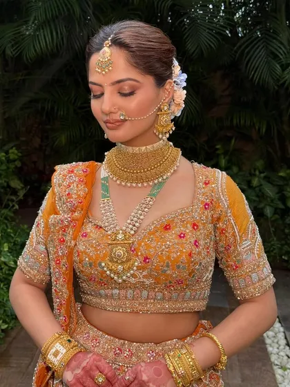 A close-up of the rust-orange bridal makeup. The soft, warm tones on the eyes and cheeks perfectly complement the unique color of the lehenga.
