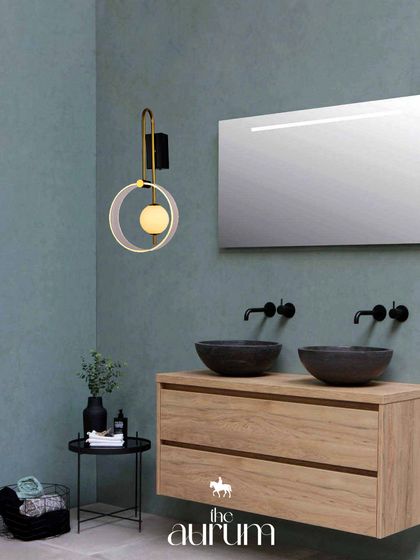 This modern, circular wall sconce adds an artistic touch to a bathroom. The design provides soft, flattering light next to the mirror, transforming a functional space into a small masterpiece.