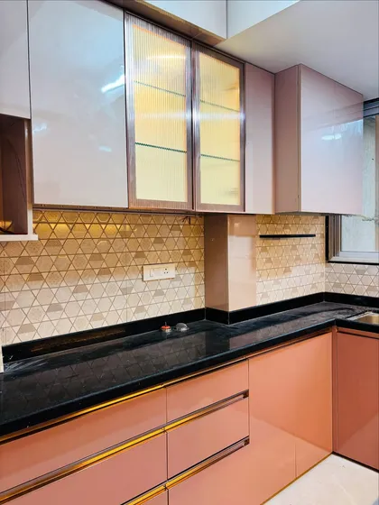 This view of the pink kitchen highlights the fluted glass overhead cabinets, which add texture and a semi-transparent look. The black granite countertop is both durable and stylish.