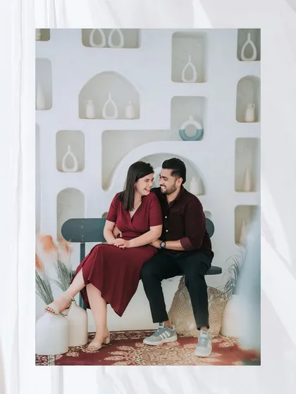 A cozy portrait of the couple on a bench in a beautifully decorated, all-white room, creating a clean and modern aesthetic.