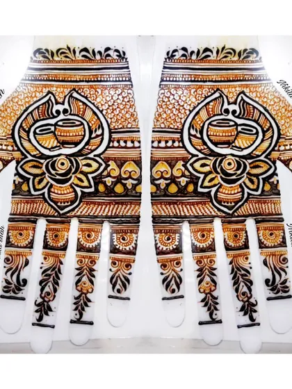 This design plays with perspective. When viewed upright, it appears as a floral pattern, but when you turn it upside down, two sacred Kalash pots are revealed. It's a creative twist on a traditional bridal palm design.