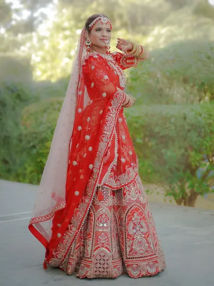 A full-length, fine-art bridal portrait showcasing the intricate details of a traditional red lehenga. I focus on classic poses and natural light to create elegant and timeless images of the bride on her special day.