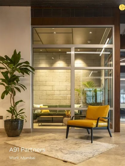 A breakout area at the A91 Partners office. The combination of a comfortable yellow armchair, a textured rug, and a view into a meeting room with stone-clad walls showcases our approach to creating diverse and engaging zones within a single office.