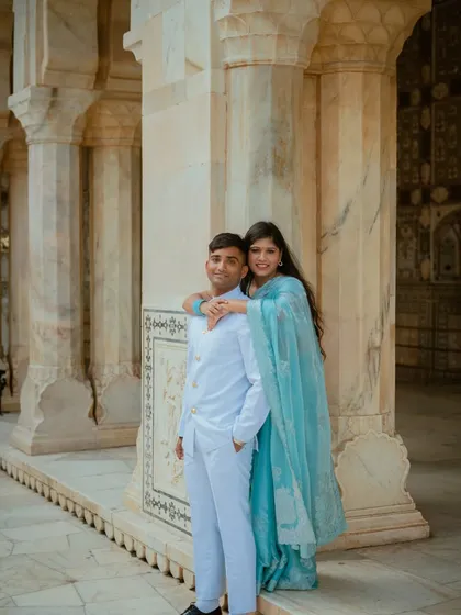 A sweet and simple pose against the marble pillars of the palace. The soft blue of the bride's saree complements the white architecture, creating a calm and loving portrait.