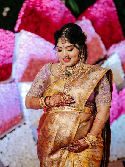 A close-up on the baby bump. The mother-to-be's hands cradle her belly, showing off the beautiful drape of her saree and the intricate details of her blouse.