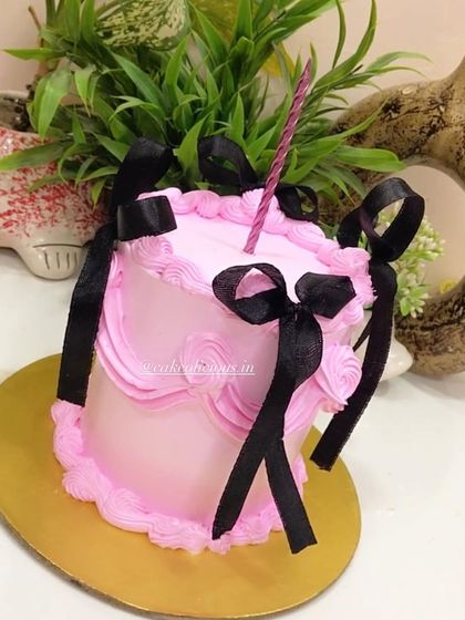 A tall, 1kg vintage cake done right. The simple pink design with black ribbon bows creates a chic and elegant look that is both modern and timeless.