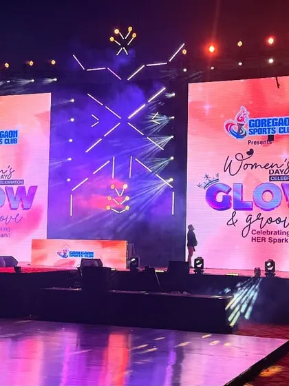 The vibrant stage for the 'Glow & Groove' Women's Day celebration at Goregaon Sports Club. We used a combination of large LED screens, custom graphics, and energetic lighting to create a fun and celebratory atmosphere for the event.
