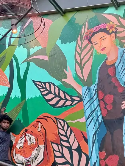 One of our team members posing with the finished Frida Kahlo piece. This shows the scale of the mural and the pride we take in our work, bringing vibrant, large-scale art to life.