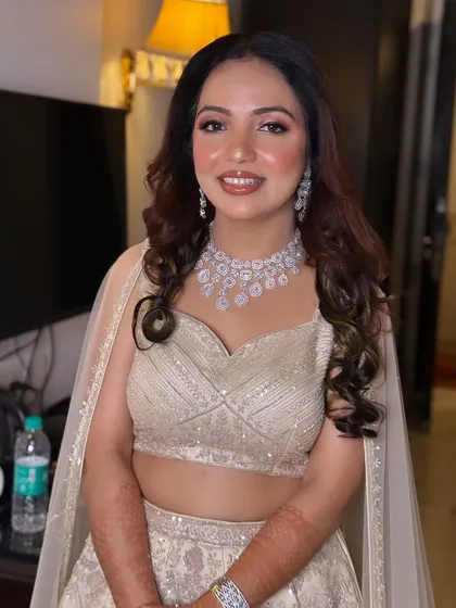 A beautiful engagement look featuring a shimmering silver lehenga. The makeup is soft and glamorous, with defined eyes and a neutral lip.