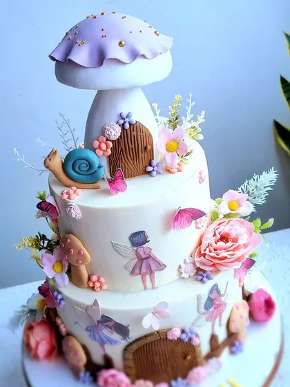 A three-tiered enchanted fairy garden cake. This design features mushroom houses, edible fairy images, and a variety of delicate sugar flowers and butterflies.