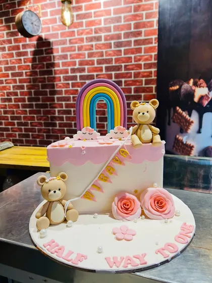 A sweet "Half way to one" cake for a 6-month celebration, featuring teddy bears and a rainbow.