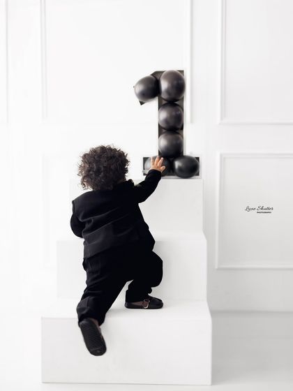 A candid moment from the minimalist first birthday shoot, capturing the little one's curiosity as he reaches for the number one.