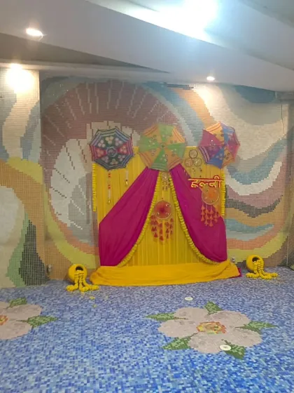 A poolside Haldi setup with a backdrop of yellow and pink drapes, decorated with Rajasthani umbrellas. The colorful mosaic tiles of the pool area complement the festive decor.